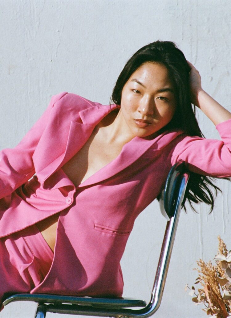 Petite model in a pink suit poses for a shoot.
